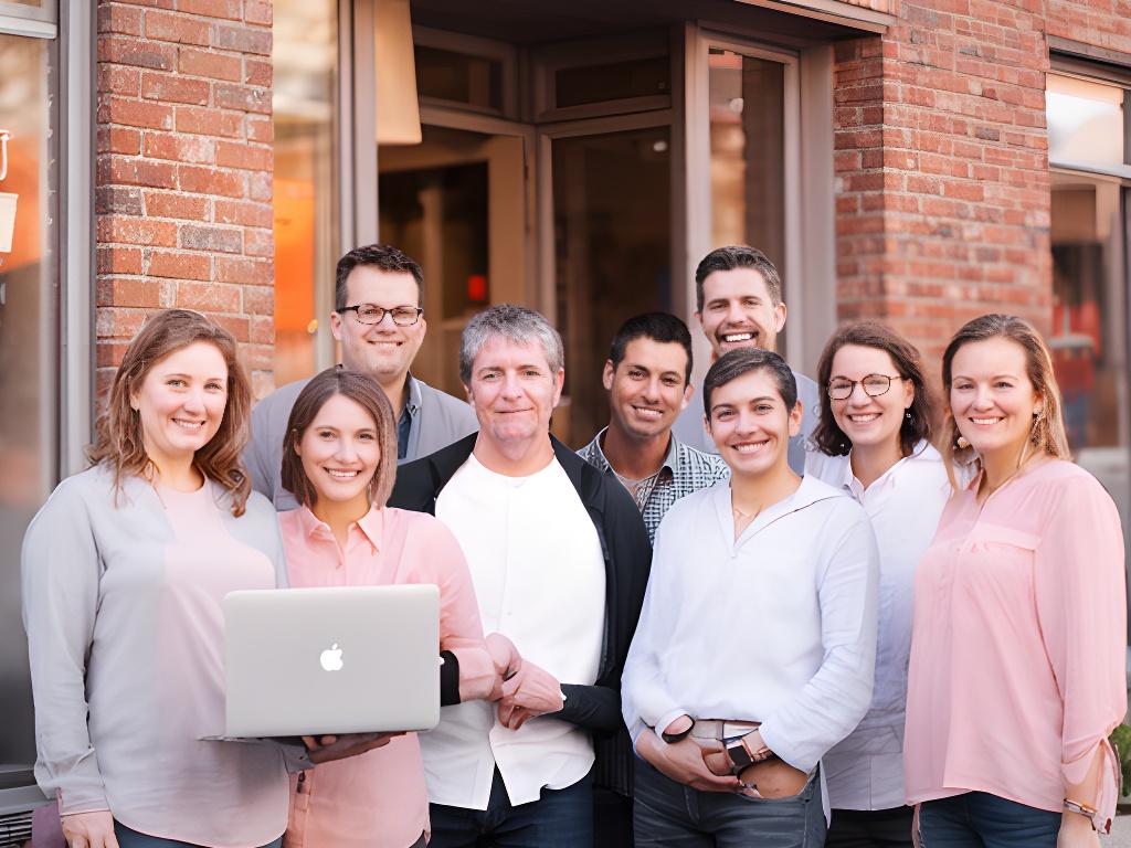 Small business founders standing outside a local brick building with a laptop and friendly expressions